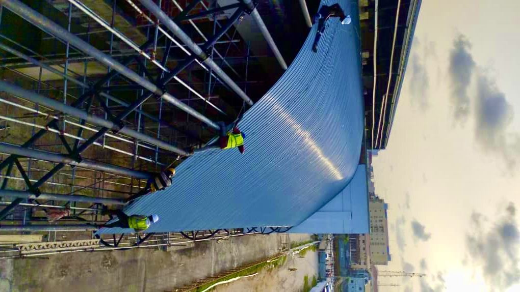Wide-angle view of curved blue aluminium roofing installation with steel framework